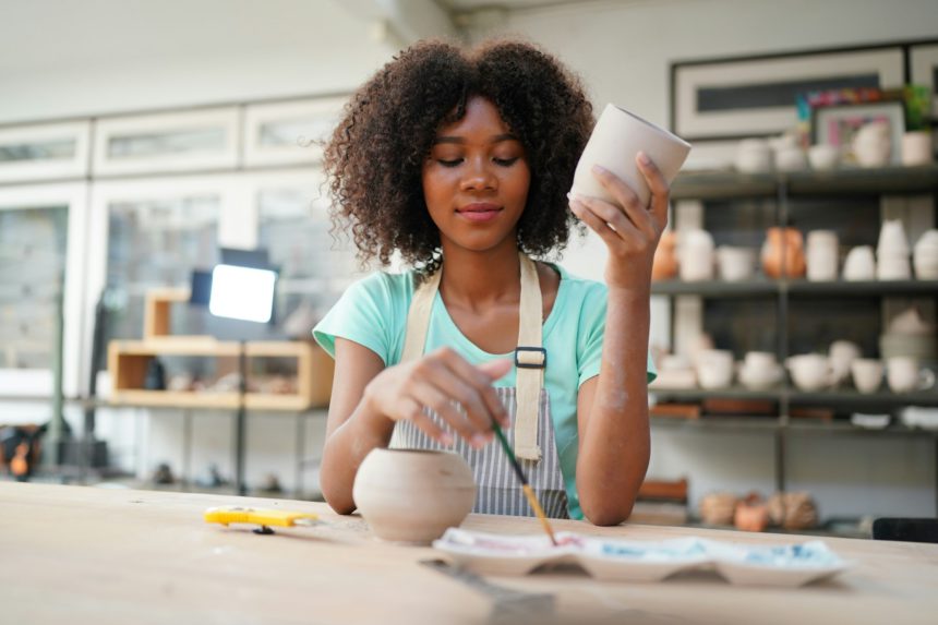 Ceramic artist painting exterior surface of pottery piece