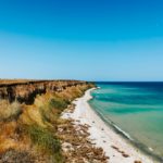 cliff sea blue aquamarine waves line sunny beach. Soft wave of ocean foam.