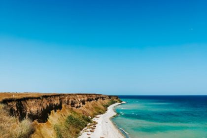 cliff sea blue aquamarine waves line sunny beach. Soft wave of ocean foam.