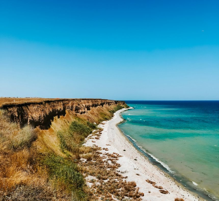 cliff sea blue aquamarine waves line sunny beach. Soft wave of ocean foam.