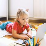 Little girl using computer online technology at home